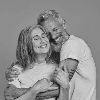 Ein älteres Paar umarmt sich lächelnd, strahlt Freude und Zuneigung aus.